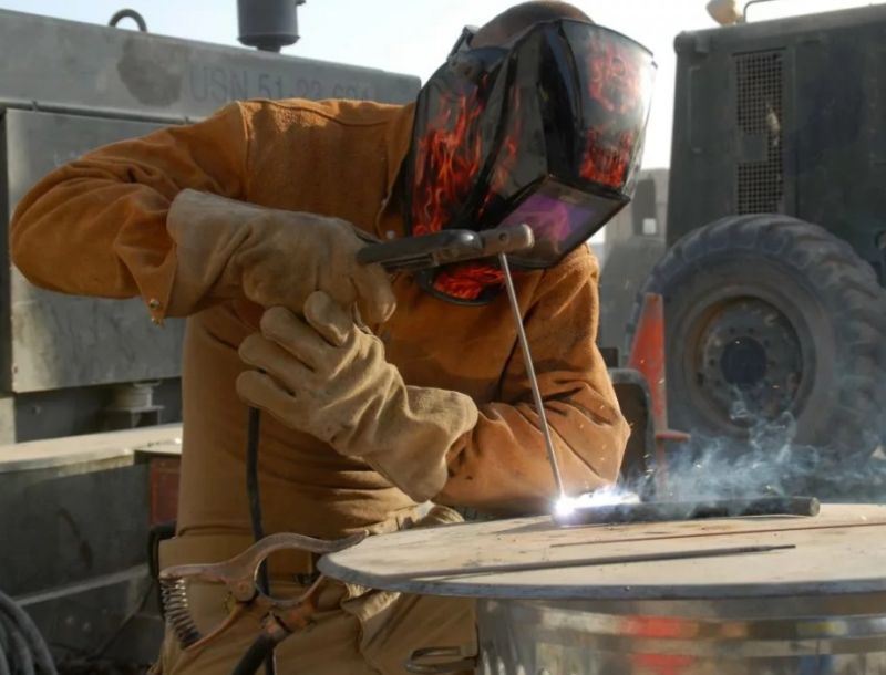 Сварщик варит трубу