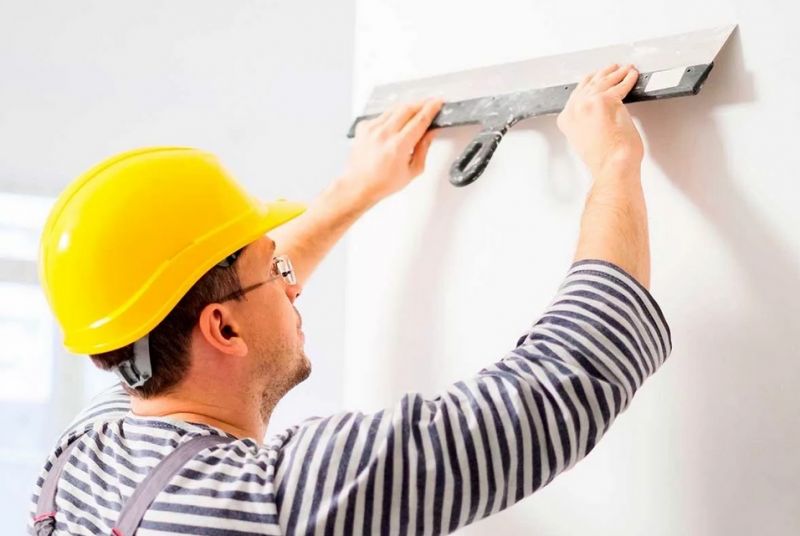 Мастер шпаклюет стену