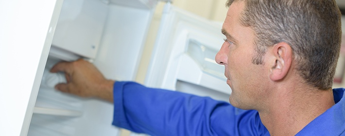 мастер проверяет работу холодильника